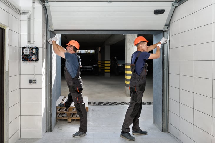 Workers installing a mechanical garage door