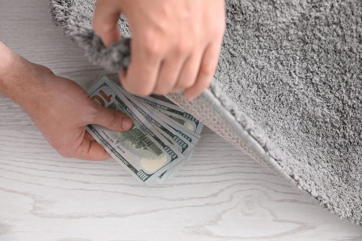 A man hides cash under a rug