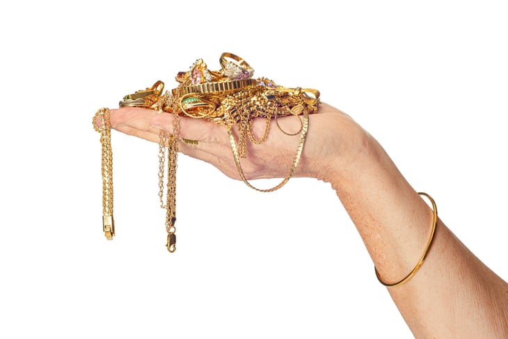 woman's hand holding a pile of gold jewelry