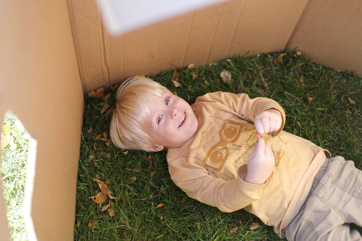 Boy playing in cardboard fort outside