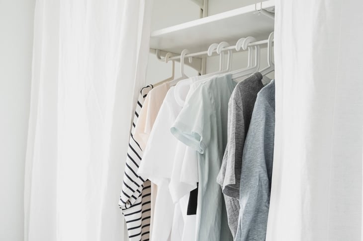 basic women's clothes on a hanger, open wardrobe with textile curtains close-up
