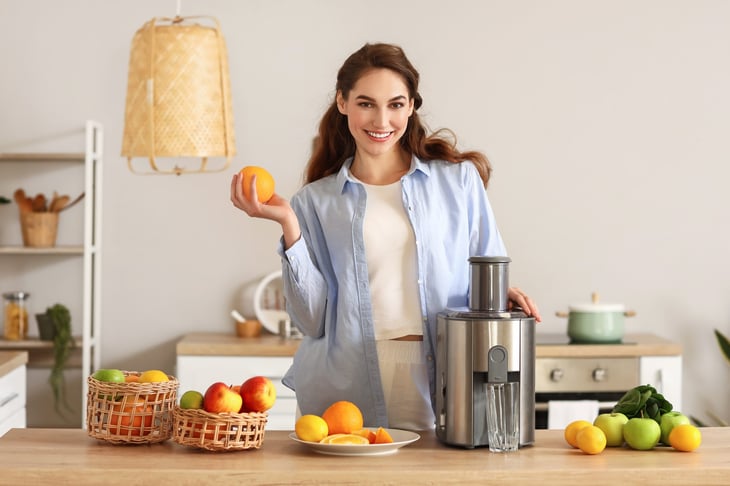 Woman with juicer in kitchen
