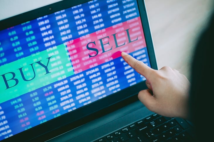 Trader's hand pointing to laptop touch screen displaying buy and sell order in stock market