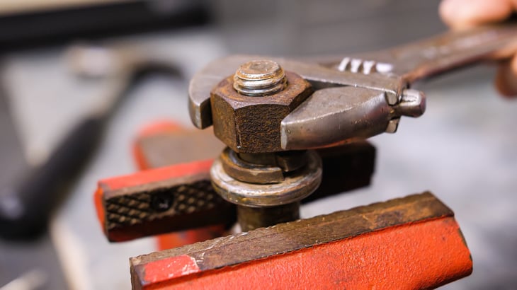 Loosening rusty bolt using an adjustable crescent wrench and vise.