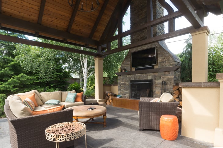 An upscale backyard terrace featuring perennials and with a custom designed shelter and fireplace.