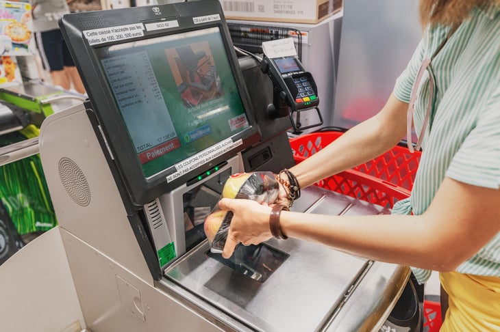Shopper using self-checkout lane at the grocery store and scanning an item's barcode