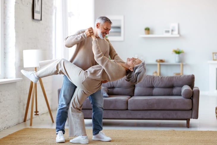 happy senior couple dancing in living room