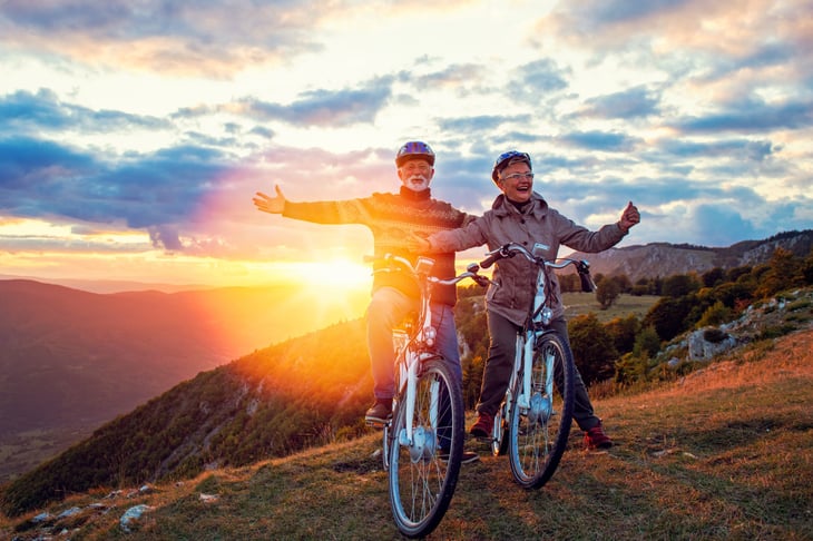 Happy senior couple on bikes enjoying retirement in the countryside