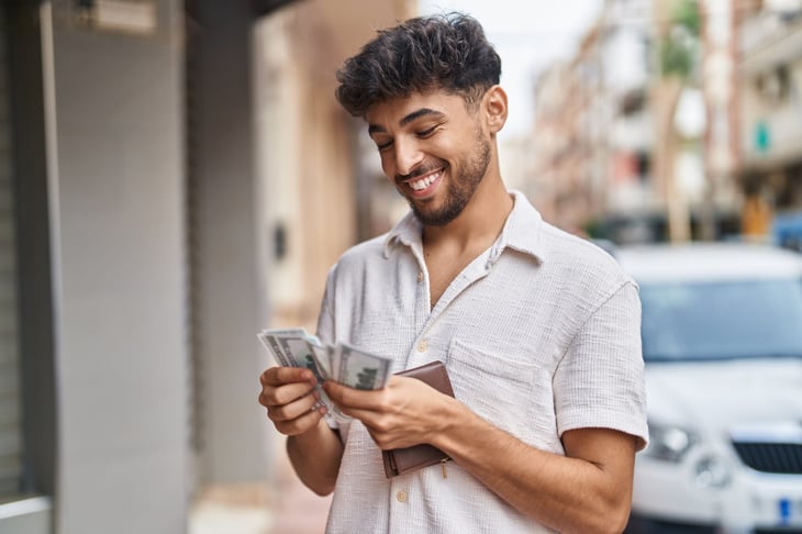 Happy man outside in town counting money saved from moving