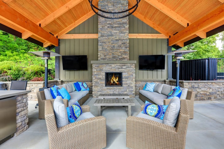 Covered patio with stone fireplace, tall chimney, wicker