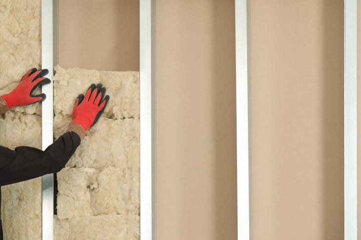 Worker installing thermal insulation material on wall