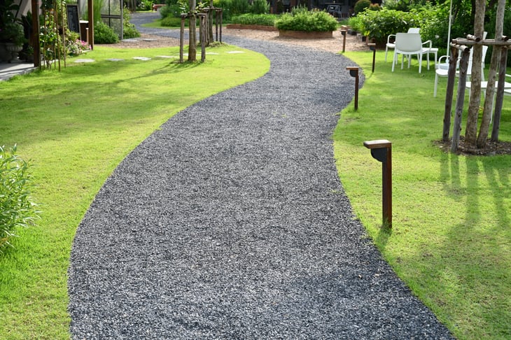 gray gravel walk path with tree and lawn in a garden