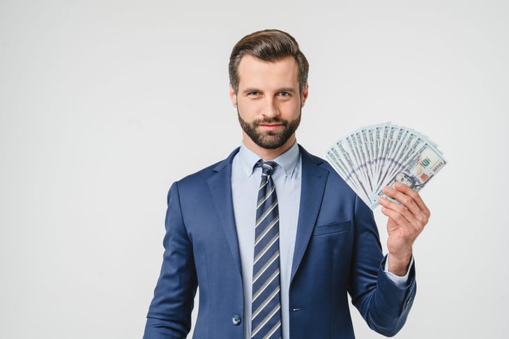 Smiling businessman is happy with a handful of money to invest