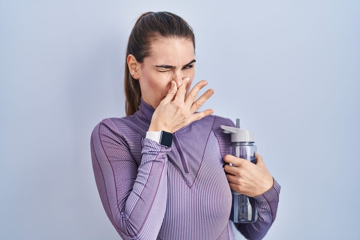 Disgusted woman with a smelly water bottle.
