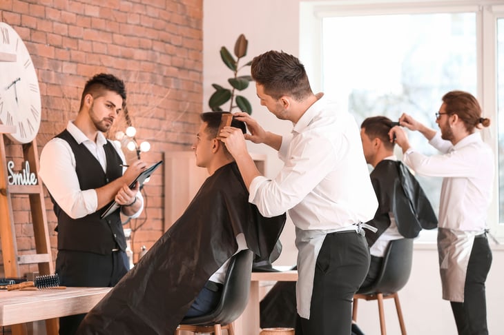Young man with professional hairdresser and model during courses in salon