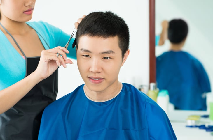 Close-up of a young man having hair cut in a salon