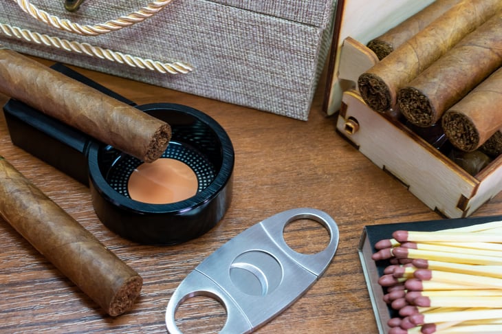 Cigar on an ashtray with accessories, a cigar humidor matches and cutter.