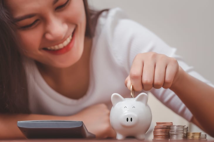 Woman happily saving money in a piggy bank