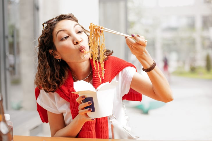 Woman eating Chinese food from takeout container