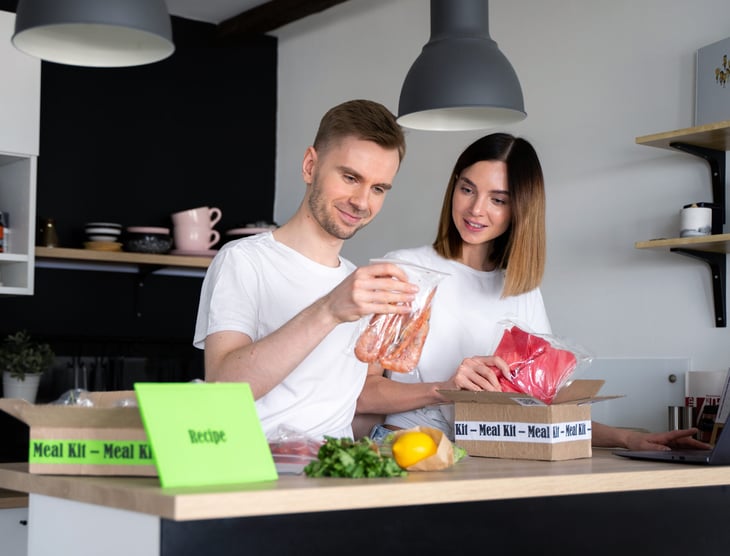 A couple unpacks a meal delivery package in their kitchen