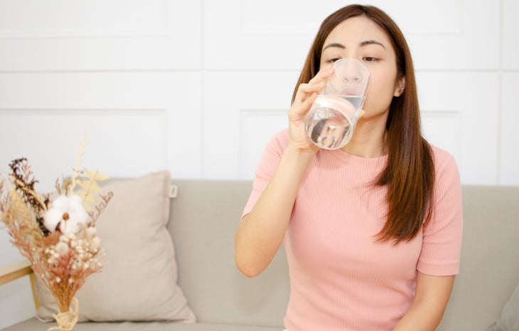 Woman drinking water at home in the summer