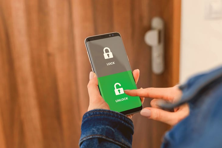 A person unlocks a door using a smart lock and mobile phone app