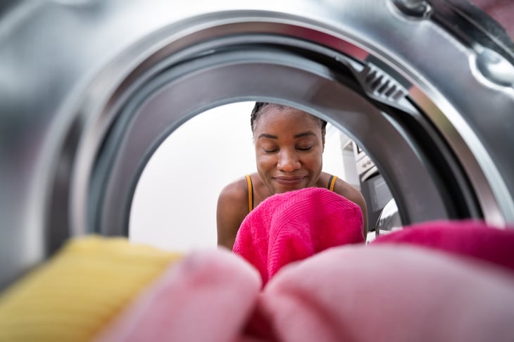woman smelling clean clothes in dryer
