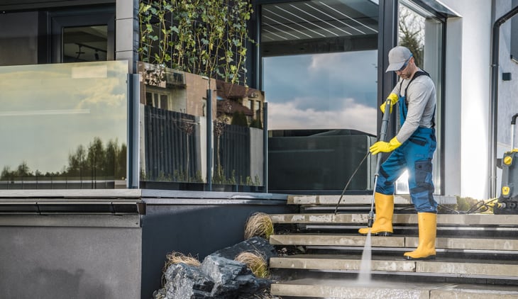 Man pressure washing the patio steps