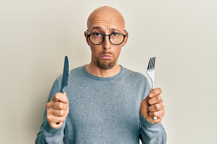 Unhappy man with a knife and fork