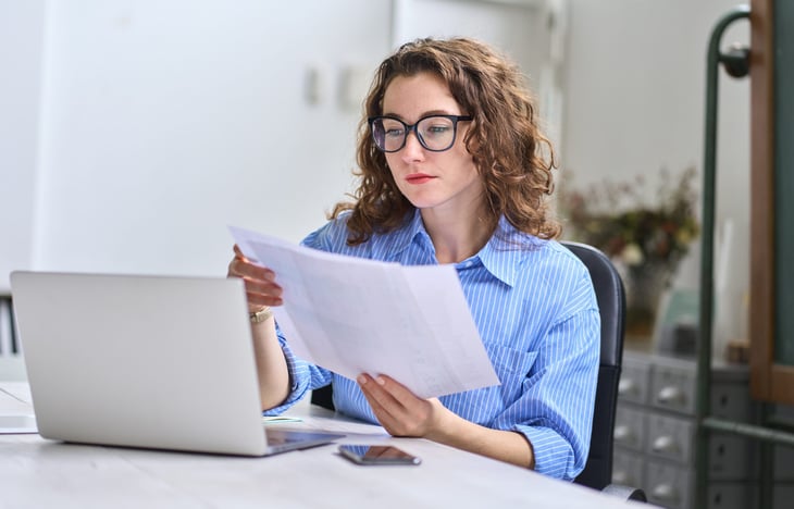 Woman looking at tax paperwork or bills on a laptop