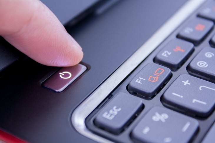 a finger is pushing a computer power button