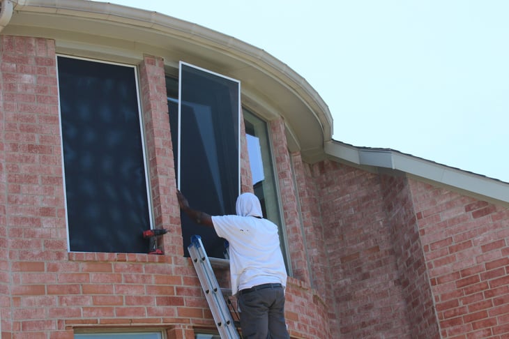 Man installing solar screen on house window