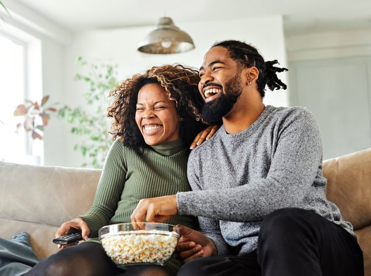 A happy young couple watching TV together at home.