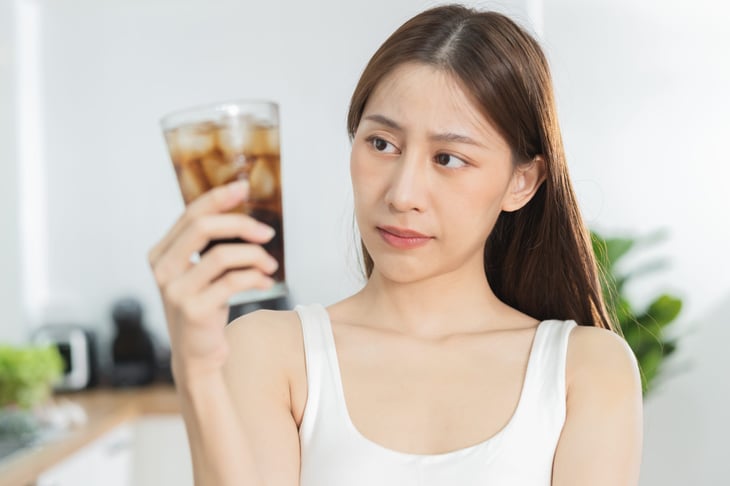woman looking skeptically at glass of soda pop