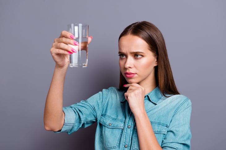 Skeptical woman looking at a glass of drinking water