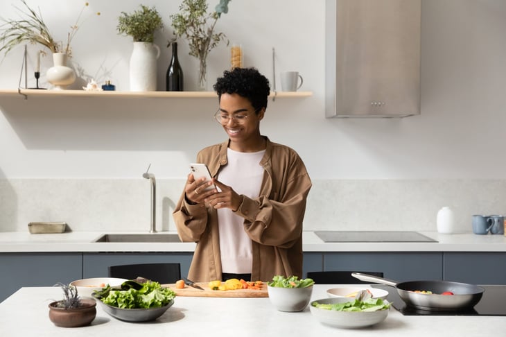 Woman using a smartphone while preparing a salad