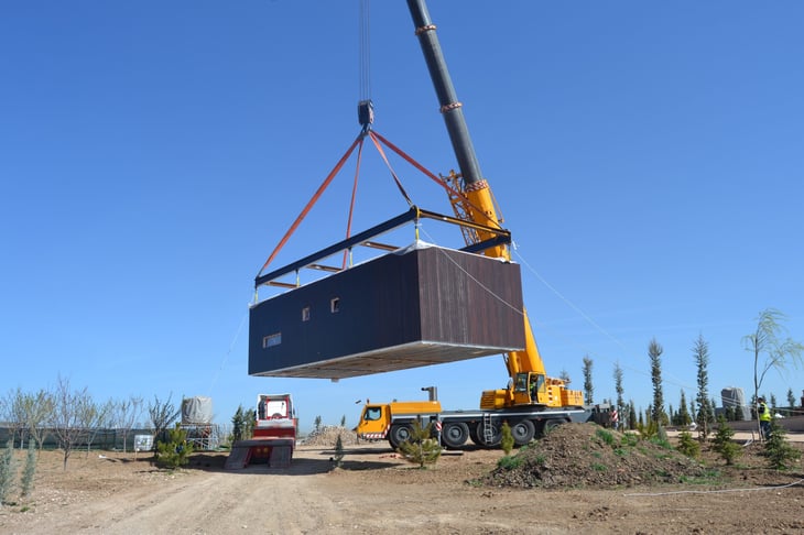 A crane lifts a prefab modular home