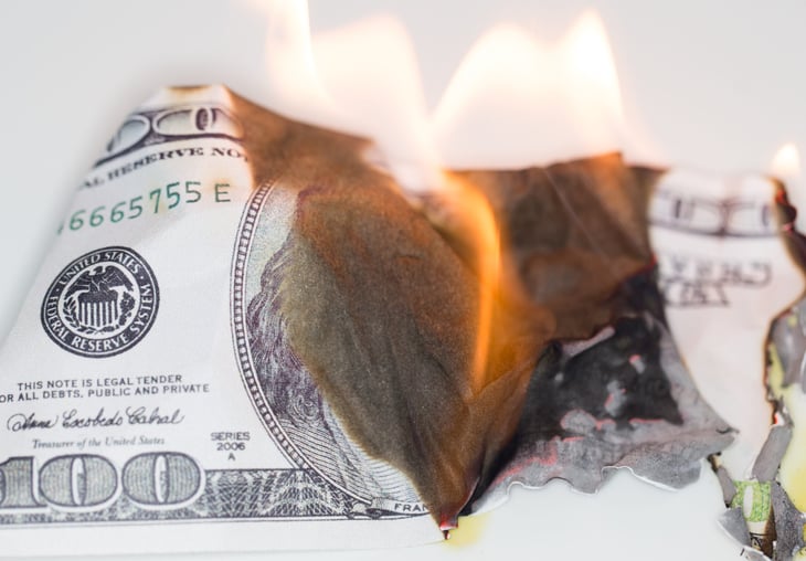 $100 bill burning to show wasted money