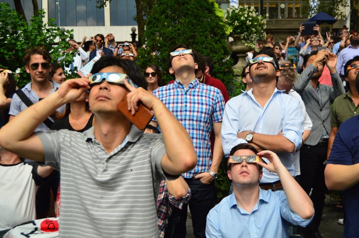 Crowd of people watching a solar eclipse with special glasses