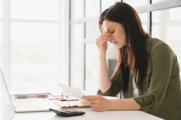 Stressed woman looking at bills and tired with a headache