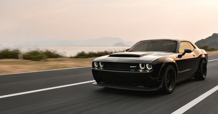 Black Dodge Challenger on a coastal road circa 2022
