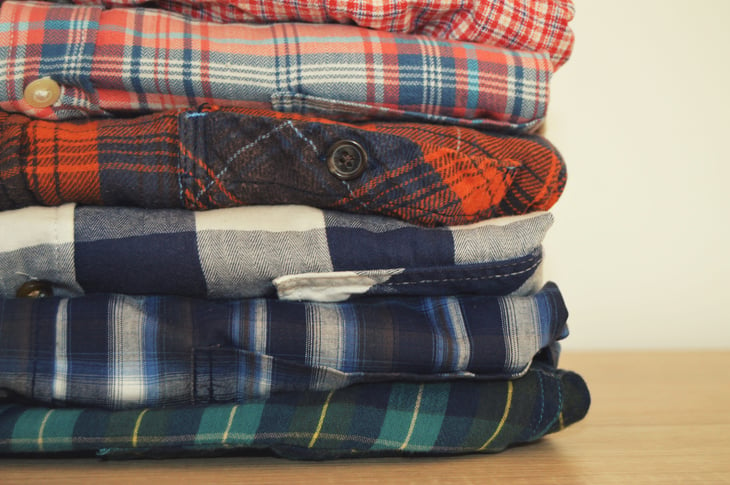 Folded flannel or Pendleton shirts stacked with colorful plaid patterns on laundry day