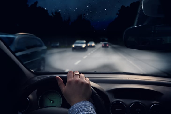 Married driver driving at night on the highway in traffic with headlights on