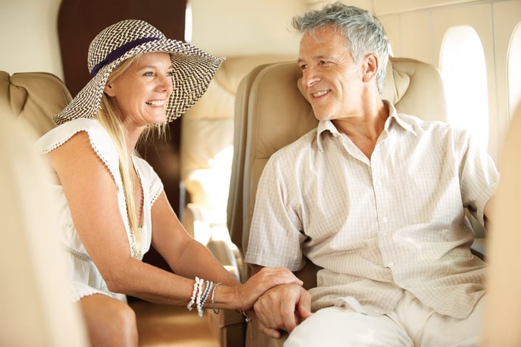 Happy senior couple in first class on plane going on vacation and traveling to an exotic place
