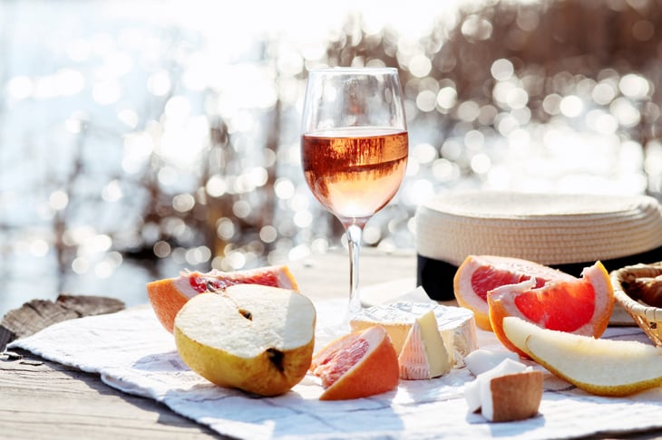 Summer picnic on the beach with rose wine, cheese, fruit, croissants.