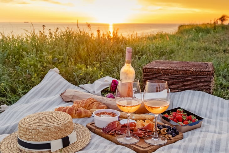 picnic with strawberries, croissants, appetizers, and rose wine.