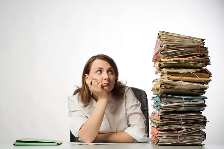 Professional woman looking at stacks of folders.