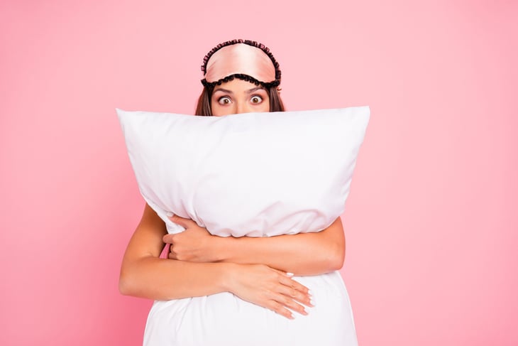 shocked woman with pillow and sleeping mask