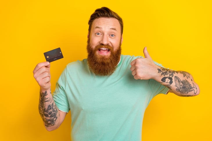 Man with a credit card giving a thumbs up