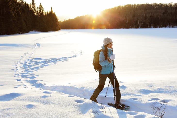 Woman walking in the snow with snow shoes and hiking poles